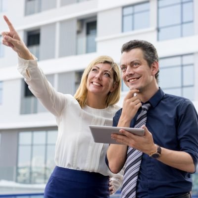 happy-lady-pointing-showing-male-colleague-something-outdoors-scaled.jpg